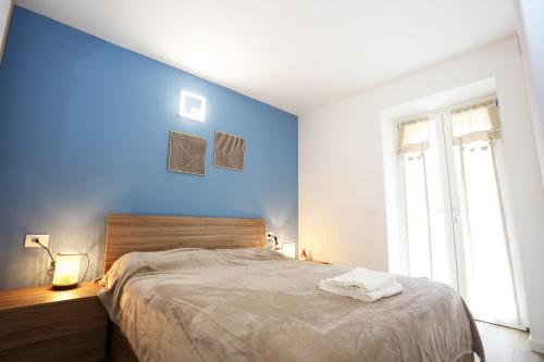Casa BEA 2 في كاستوني ديلا بريسولانا: غرفة نوم بجدران زرقاء وسرير مع منشفتين