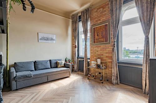 a living room with a couch and a brick wall at Rustic Gallery Apartment with Panoramic View and AC in Budapest