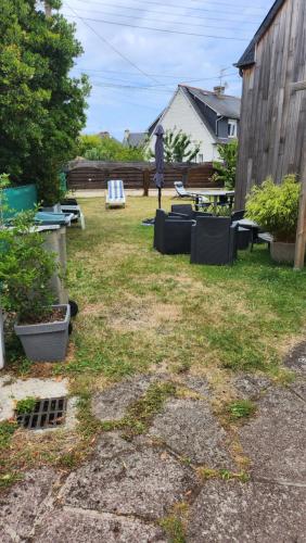 a backyard with chairs and tables and a fence at Charmante maison in Dinard