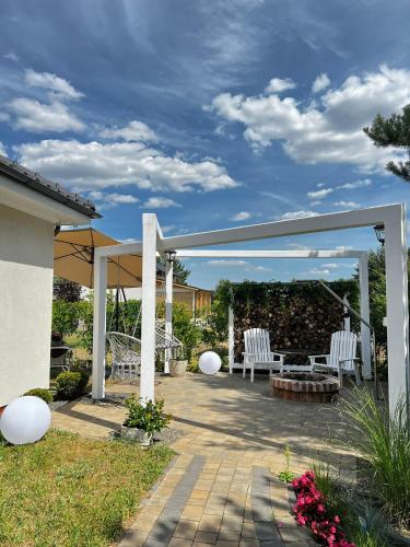 a patio with two white chairs and a pergola at Sosenkowe Apartamenty in Kuźnica Głogowska