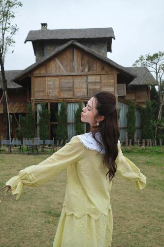 a woman in a yellow dress standing in front of a house at M-Stay Thạch Thất Hà Nội in Ðào Lãng