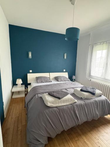 a bedroom with a large bed with a blue wall at Charmante maison in Dinard