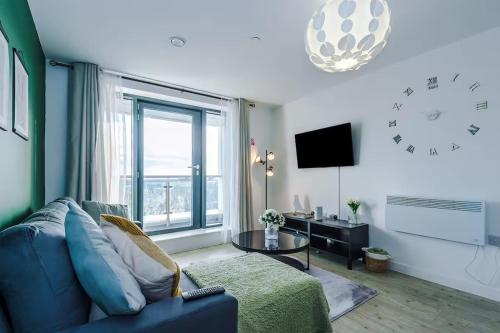 a living room with a blue couch and a large window at Quayside Living in Manchester