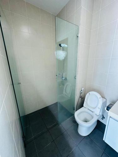 a bathroom with a toilet and a glass shower at Southbay Seaview Condo A31 #10minQueensbay in Bayan Lepas