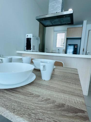 a kitchen counter with white bowls on a wooden table at Southbay Seaview Condo A31 #10minQueensbay in Bayan Lepas