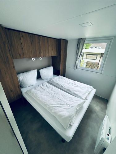 a small bedroom with a white bed with a window at Mobilheim 90 in Hüde