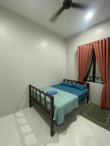 a bedroom with a bed and a ceiling fan at Permai Homestay in Kampong Burok