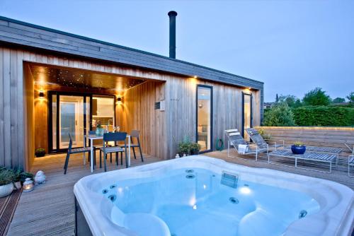 a hot tub on the deck of a house at Pamela's Meadow, Strawberryfield Park in Cheddar