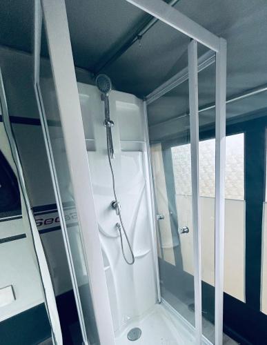 a shower in a bathroom with a glass door at Mietwohnwagen 54 in Hüde