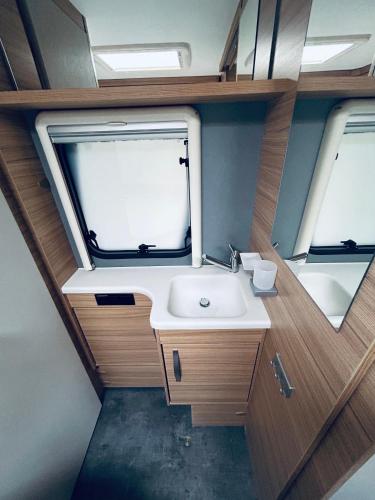 a bathroom with a sink and two windows at Mietwohnwagen 54 in Hüde