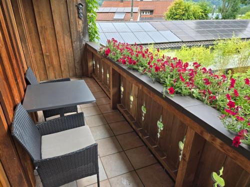a balcony with a table and chairs and flowers at Ferienwohnungen beim Silbergersee in Oberaudorf