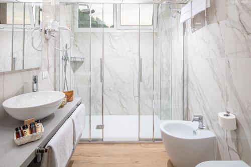 een witte badkamer met een wastafel en een douche bij Hotel Bembo in Bibione