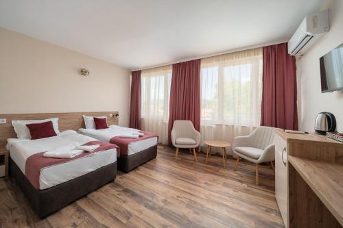 a hotel room with two beds and a television at Хотел Орфей in Kŭrdzhali