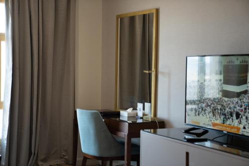 a hotel room with a desk and a television at Saja Al Madinah in Al Madinah