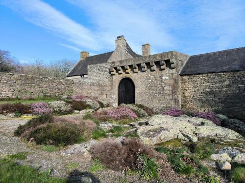 an old stone building with a door in a garden at Manoir de Kerenneur in Plourin