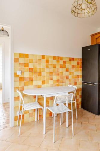 une cuisine avec une table, des chaises et un réfrigérateur dans l'établissement appartement proche paris et Roissy, à Persan