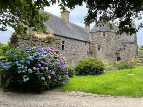 an old stone building with flowers in front of it at Manoir de Kerenneur in Plourin