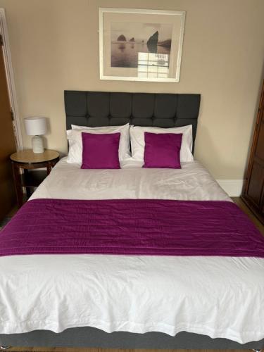 a bedroom with a large bed with purple sheets and pillows at The Bell Inn in Cheltenham
