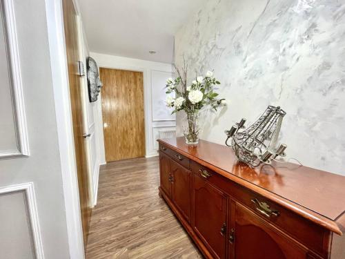 a room with a dresser with a vase of flowers on it at Spacious, smart apartment near City Centre and Coop Arena Free parking in Manchester