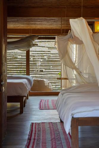 a room with three beds and a window at Eco Lodge Mancora in Máncora