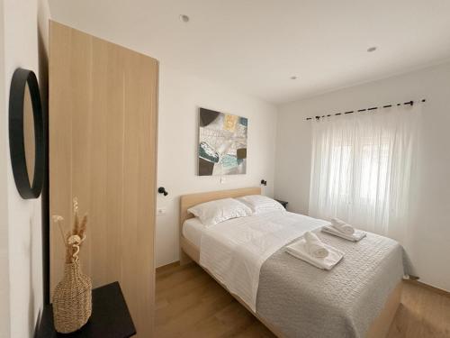 una camera da letto bianca con un letto e una finestra di Beachfront house Miamore - 10 m from the sea a Mrljane