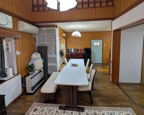 a dining room with a white table and chairs at 木漏れ日和静寂の森の別荘 in Nasu