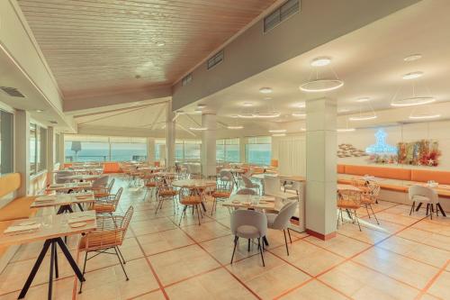 a restaurant with tables and chairs and the ocean at Talaso Atlántico in Mougás
