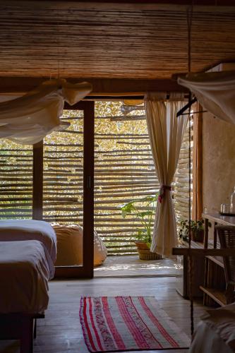 a bedroom with a bed and a window with curtains at Eco Lodge Mancora in Máncora
