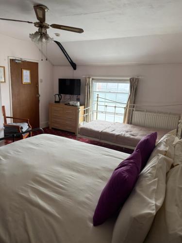 a bedroom with a large white bed with purple pillows at The Bell Inn in Cheltenham