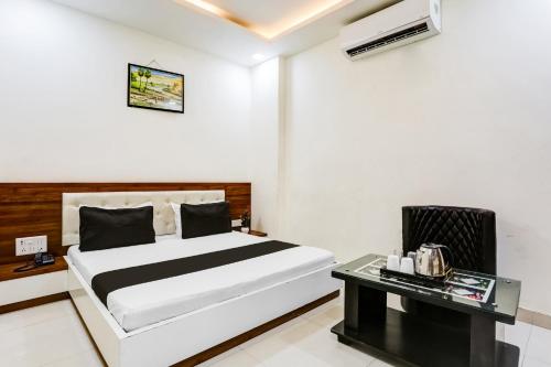 a white bedroom with a bed and a table at Super Hotel O Green in Hisār