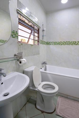 a white bathroom with a toilet and a sink at Nzubo Experience in Livingstone