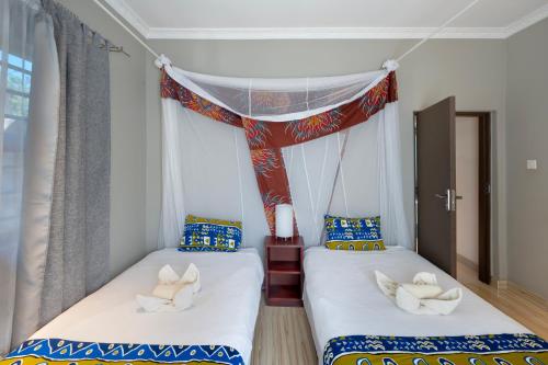 two twin beds in a room with a window at Nzubo Experience in Livingstone