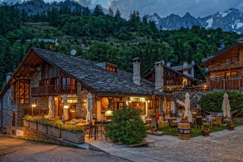 a house in the mountains with tables and chairs at Hotel Pilier D'Angle & Wellness in Courmayeur