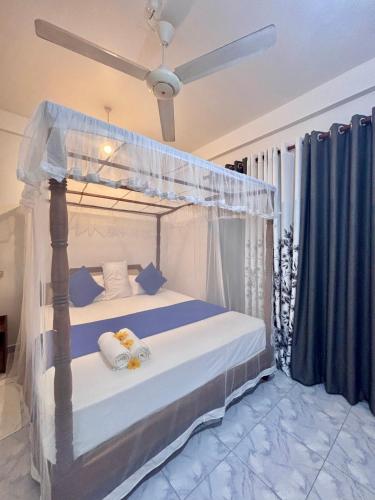 a bedroom with a canopy bed with blue pillows at Lake View Villa - Tangalle in Tangalle