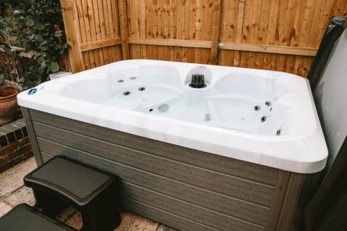 a bath tub sitting next to a wooden wall at Romantic Country Cottage with Private Hot Tub in Rowde