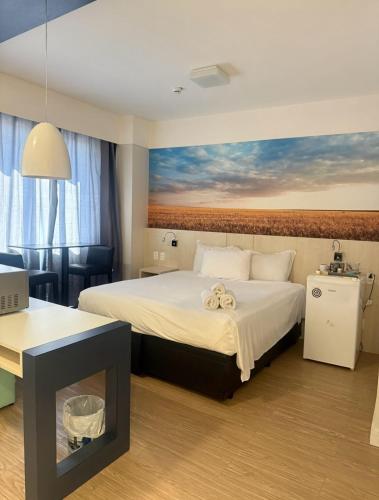 a hotel room with a bed with a painting on the wall at Flat em Alphaville in Barueri