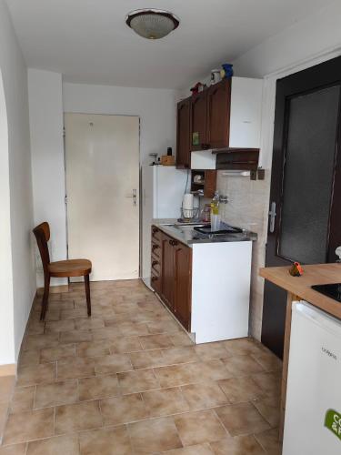 a kitchen with white appliances and a table and a chair at SunsetHouse Garden Apartment in Banka