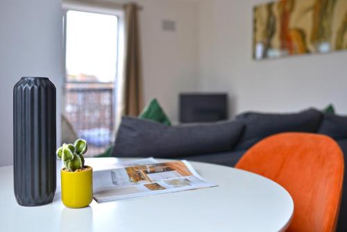 a white table with a vase and a plant on it at Broad Gauge Apartments in Wolverhampton