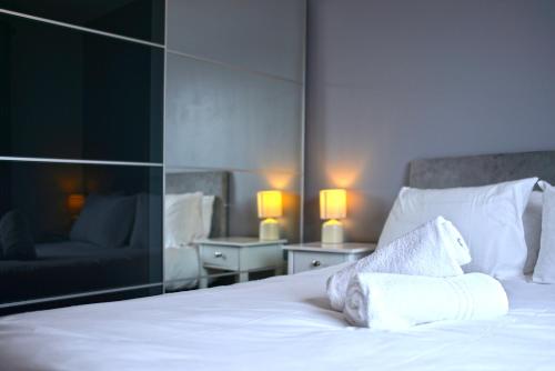 a bedroom with a bed with white sheets and pillows at Broad Gauge Apartments in Wolverhampton