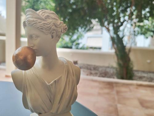 a statue of a woman eating an apple at CORFU TENNIS Studios in Agios Rokkos