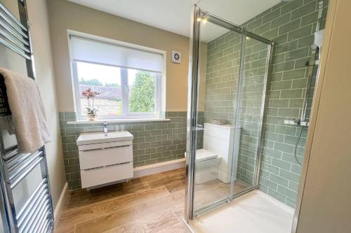 a bathroom with a shower and a toilet and a window at Wellingtonia Cottage in Chirbury
