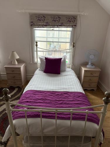 a bedroom with a bed with a purple blanket and a window at The Bell Inn in Cheltenham