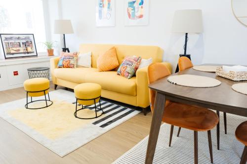 a living room with a yellow couch and a table at Carcavelos Beach 12 in Carcavelos