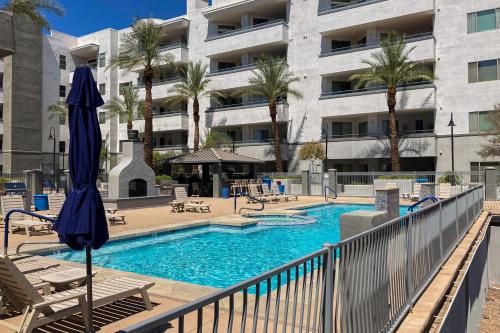 a pool with chairs and an umbrella next to a building at The Water’s Edge - Condo 3025 in Tempe