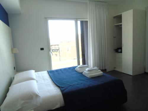 Schlafzimmer mit einem Bett mit blauer Bettwäsche und einem Fenster in der Unterkunft Areté Luxury Room in Reggio di Calabria