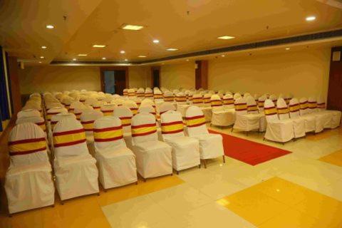 a room with rows of white chairs and tables at Dhanunjayas Luxury Hotel in Hosūr