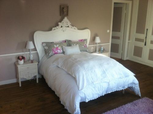 a bedroom with a white bed with a white headboard at O Mylle Douceurs in Le Crotoy