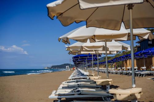 a row of lounge chairs and umbrellas on a beach at Riva Del Sole Resort & SPA in Castiglione della Pescaia