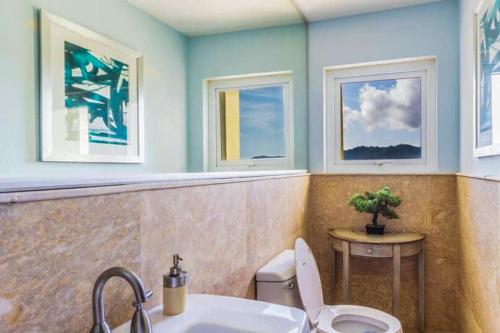 a bathroom with a toilet and a sink and two windows at Acqua 801 in Jacó