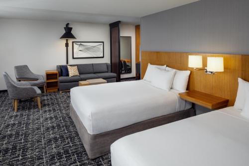 a hotel room with two beds and a couch at Hyatt Place Chicago Midway Airport in Bedford Park